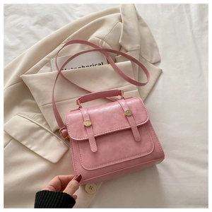 Borsa a tracolla in pelle PU rosa testurizzata con bottoni dorati su un blazer beige