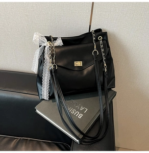 Detail der schwarzen Hobo-Tasche mit goldenem Drehverschluss und weißem Spitzenband
