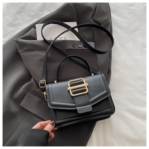 Détail d'un sac à main minimaliste en similicuir noir avec une boucle carrée dorée