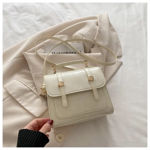 Dettaglio di una borsa a mano minimalista crema con fibbie metalliche dorate lucide