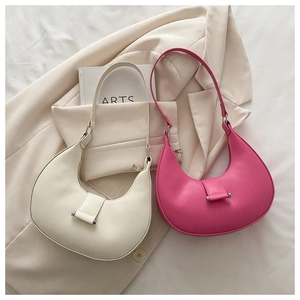 Detail of minimalist leather crescent shoulder bags in cream and magenta on a blazer