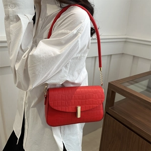 Retro red crocodile embossed leather underarm bag with gold hardware on a female model