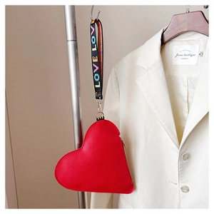 Detail der roten herzförmigen Ledertasche mit LOVE-Gurt an weißem Anzug