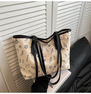 Detail of a large tote bag with cartoon puppy print and black trim on white leather