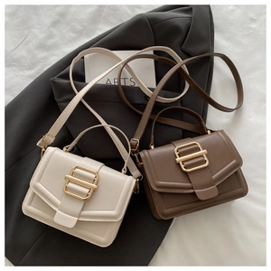 Détail de sacs bandoulière beige et marron avec grandes boucles dorées carrées