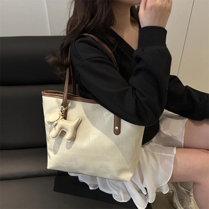 Borsa tote beige minimalista con cuciture geometriche, tracolle marroni e ciondolo cane