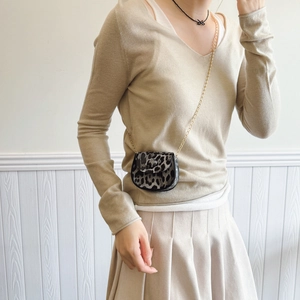 Mini leopard print crossbody bag with gold chain strap shown on a cream knit outfit