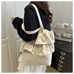 Modella che indossa una borsa tote in tela beige con grandi dettagli a volant