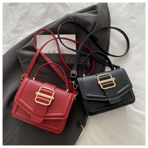 Détail de sacs carrés rouges et noirs avec boucles dorées sur un blazer gris