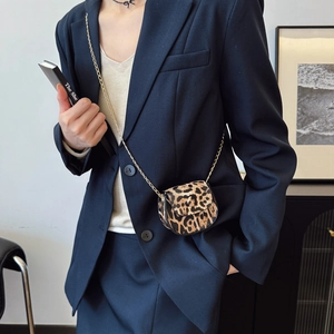 Mini leopard print saddle bag with gold chain strap worn by model in casual style