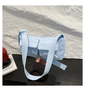 Dettaglio borsa a tracolla in nylon trapuntato azzurro con due tasche frontali a patta