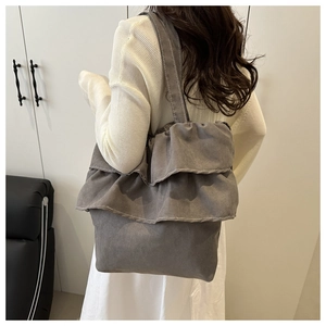 Detail of dark grey ruffle shoulder bag featuring layered fabric and white contrast stitching