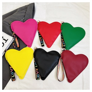 Detail bunter herzförmiger Handtaschen mit Litschistruktur und LOVE-Schriftzug am Handgelenk