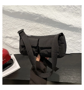 Dettaglio della borsa a tracolla in nylon nero con due tasche a patta e tracolla regolabile