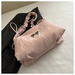 Détail du sac rose pâle avec texture plissée marbrée et breloque noeud argenté