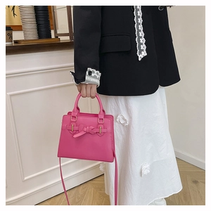 Vue détaillée du sac à main rose vif avec décoration de nœud et détails dorés