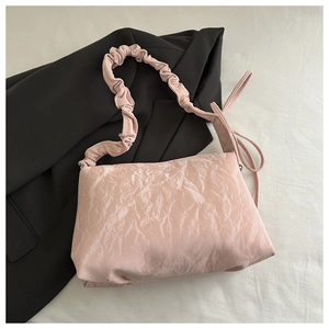 Détail du sac à bandoulière plissé rose clair avec bandoulière scrunchie sur fond noir