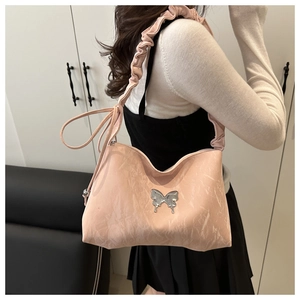 Détail du sac à bandoulière en cuir plissé rose avec un ornement papillon en argent