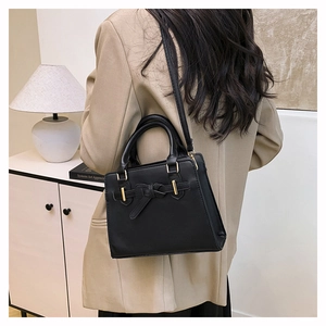 Détail du sac bandoulière noir avec boucle à nœud et garnitures dorées sur modèle