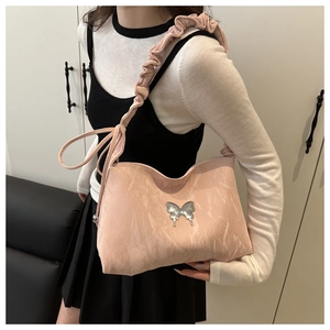 Détail d'un sac rose avec décoration papillon argenté et bandoulière à plis froncés