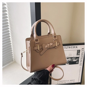 Détail du sac bandoulière beige élégant avec nœud en cuir et poignées rigides