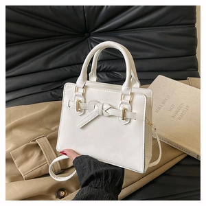 Vue détaillée du sac en cuir blanc avec nœud élégant et finitions métalliques dorées