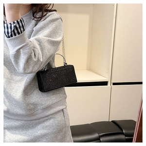 Close-up of black sequined handbag with silver metal ring handle on model indoors