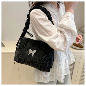 Détail du sac bandoulière plissé noir avec breloque papillon argentée et bandoulière froncée