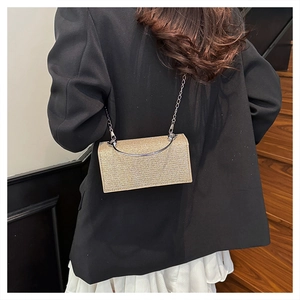 Detail of champagne gold sequined handbag with metal handle on black blazer suit