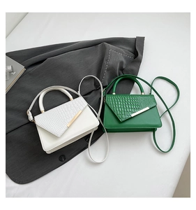 Detail view of stylish square crossbody bags in white and green with faux crocodile texture