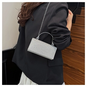 Silver rhinestone evening clutch bag with metal handle worn by model against a suit