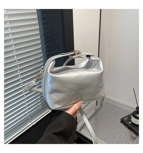 Detail of silver metallic quilted handbag with gold hardware and top handle strap
