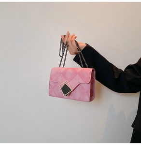 Detail of pink denim texture bag with black gold geometric lock and chain strap