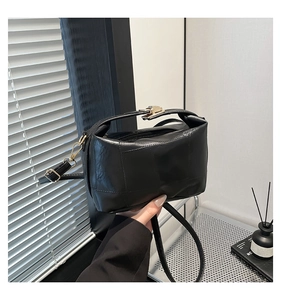 Close-up of black rectangular shoulder bag with vintage texture and gold hardware