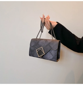 Detailed macro view of dark grey twill texture and square metal clasp on chain bag