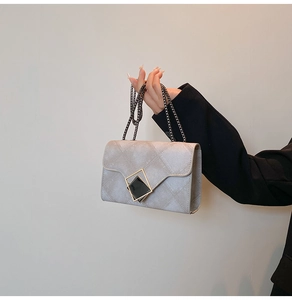 Detailed macro view of the grey quilted crossbody bag with a gold geometric buckle lock