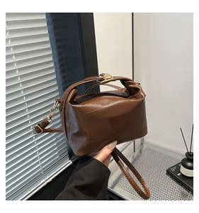 Detail of a brown textured PU leather bag with retro metal clasp and golden hardware hooks