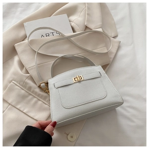 Detail of white litchi grain texture and gold twist lock on women's crossbody bag
