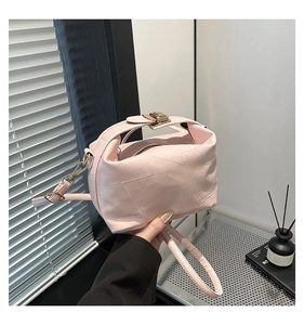 Close-up of light pink puzzle shoulder bag showing pebbled leather and gold metal buckle