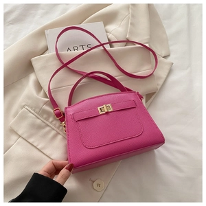 Detail of rose red lychee texture leather bag with gold buckle on beige blazer background