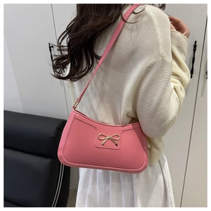 Gros plan d'un sac porté épaule rose avec boucle nœud doré sur un mannequin femme