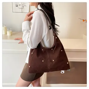 Sac cabas en daim marron à clous dorés porté à l'épaule pour référence de taille