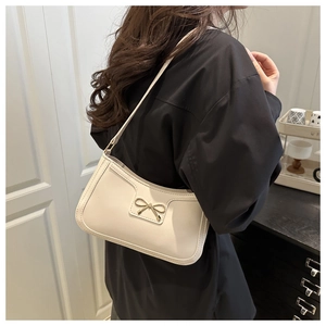 Détail d'un sac demi-lune blanc crème avec boucle dorée sur une tenue noire
