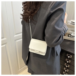 Chic white leather crossbody bag shown on model with dark grey blazer and minimalist style
