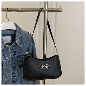 Vue détaillée du sac baguette noir avec boucle nœud en métal doré sur un cintre