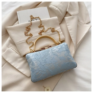 Close-up of light blue floral embroidery with rhinestone butterfly clasp and gold chain