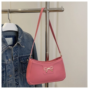 Sac sous le bras rose en similicuir avec nœud métallique suspendu avec une veste en jean