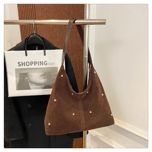 Gros plan d'un sac hobo en daim marron avec rivets dorés et forme de demi-lune rétro