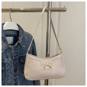 Détail d'un sac à bandoulière crème avec boucle nœud dorée et texture cuir lisse