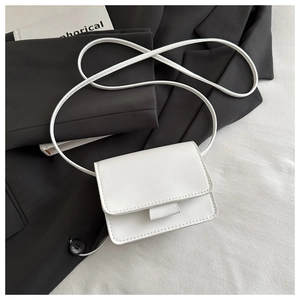 Detail of a minimalist white crossbody mini bag with matte texture on black blazer